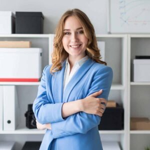 Beautiful young girl stands near a rack in the office. Charming young girl in a blue jacket and white blouse. photo with depth of field